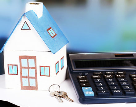 Calculator next to a miniature house and keys