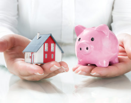 Person holding a toy house and piggy bank