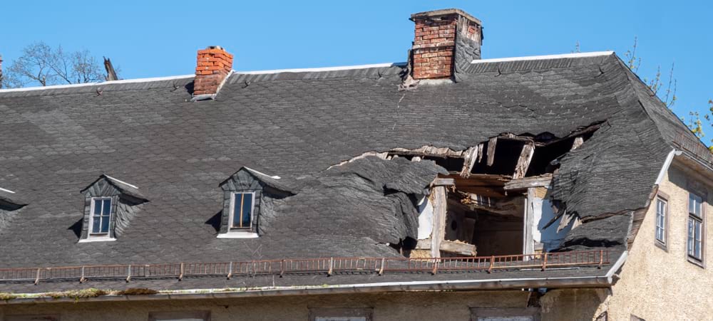 photo of roof with large hole in it exposing the inside of the property. 