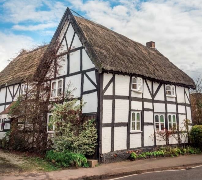 photo of Tudor-style timber framed building with thatched roof