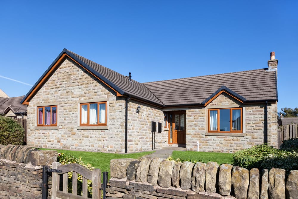 photo of a stone bungalow and its front garden and stone wall